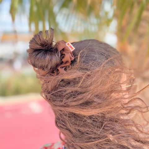 Person with long hair blowing in the wind under a palm tree