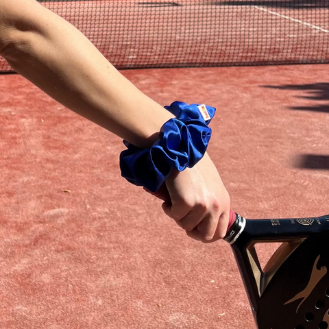 Woman holding a racquet on a tennis court with palm trees in the background