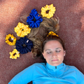 Woman lying on a track with blue and yellow hair accessories around her head.