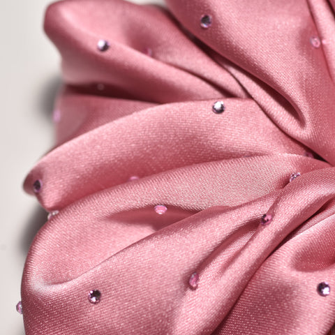Close-up of a pink scrunchie with small embellishments on a light background